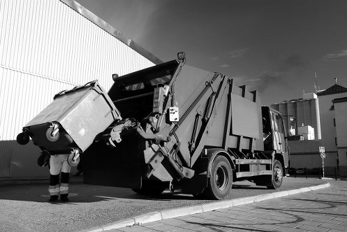Team loading a skip with safe lifting techniques and visible safety signage